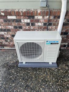 Daikin outdoor air conditioning unit installed on exterior brick wall by Acorn Heating and Cooling.