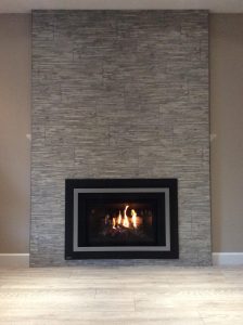 Modern gas fireplace with stone surround installed by Acorn Heating and Plumbing.