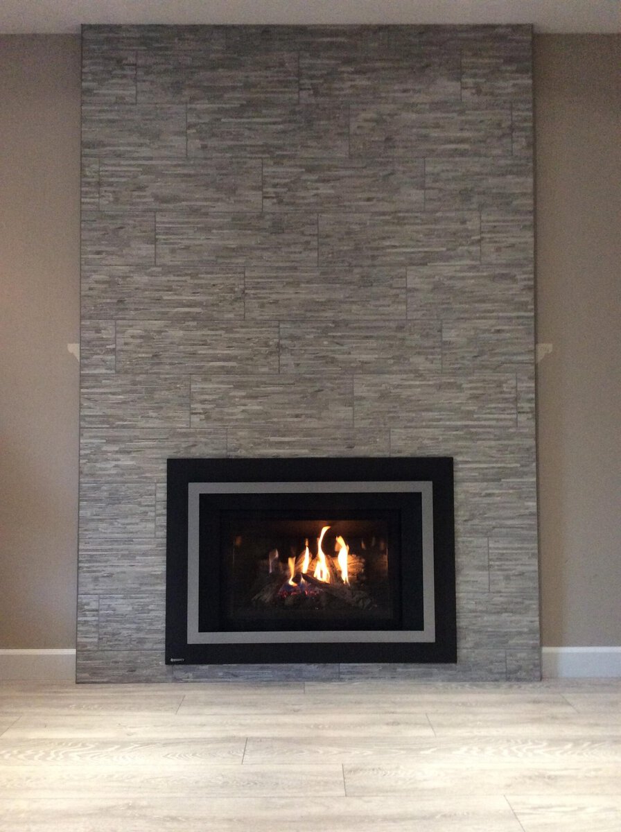 Modern gas fireplace with stone surround installed by Acorn Heating and Plumbing.